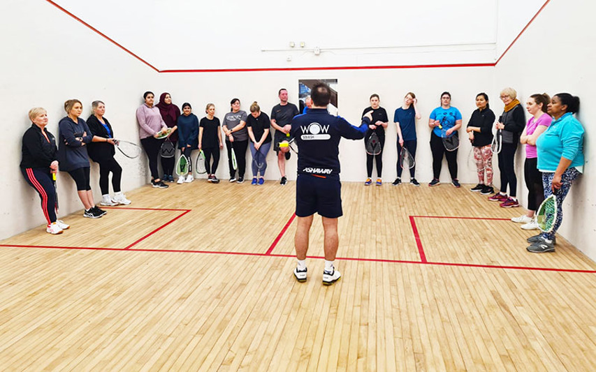 Women and men standing together on a squash court